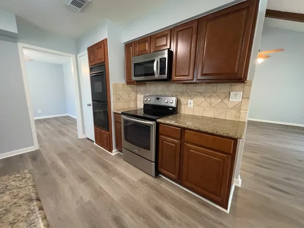 a kitchen with stainless steel appliances granite countertop a stove microwave and refrigerator