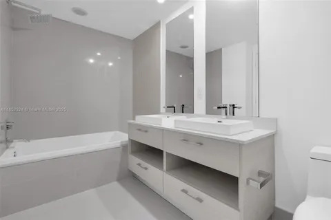 a bathroom with a double vanity sink mirror and bathtub