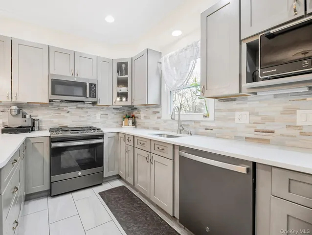 a kitchen with granite countertop a sink dishwasher stove and microwave
