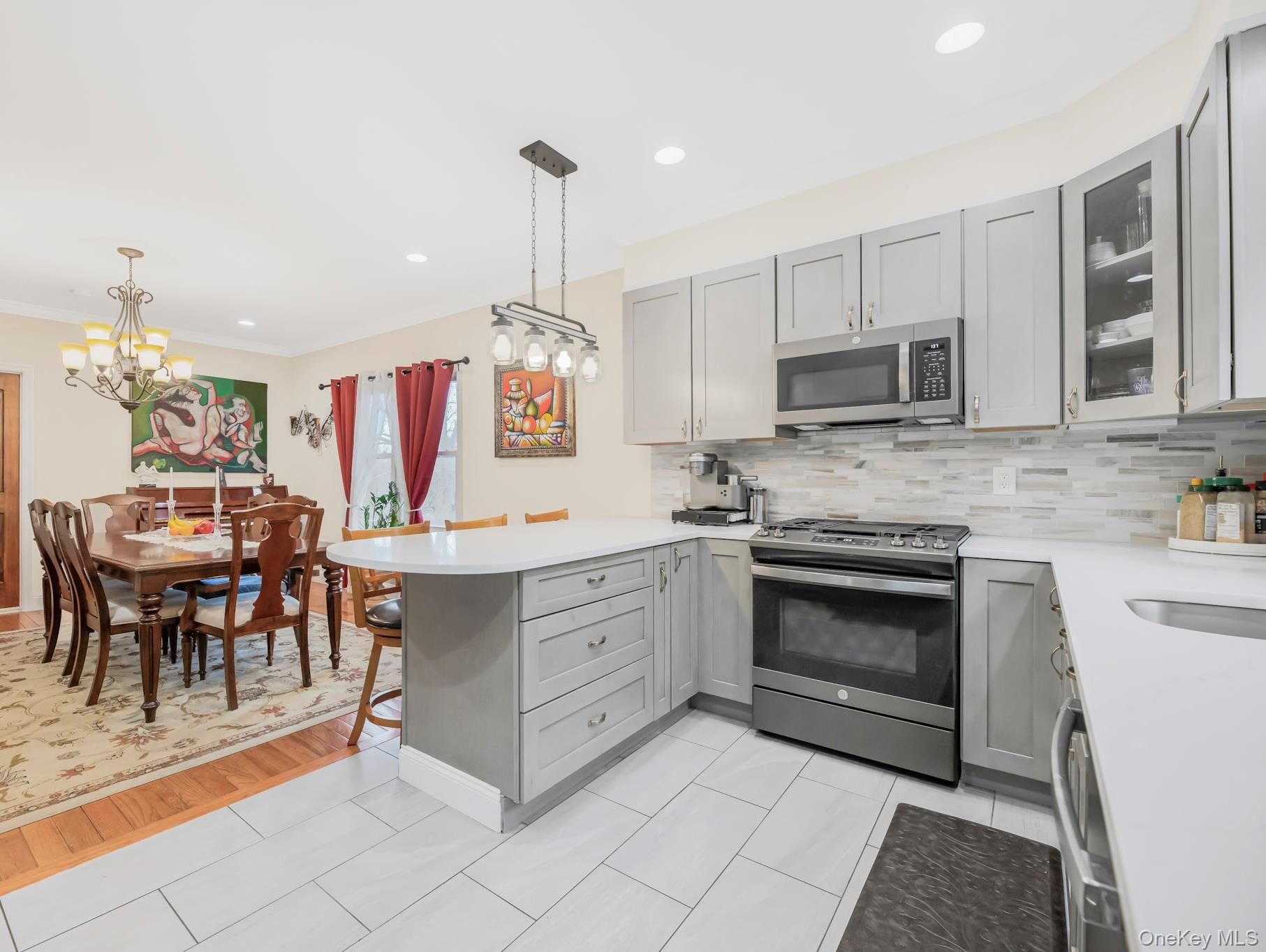 248 Rockne Road Yonkers, NY 10701 - Photo 12 of 40 Kitchen featuring gray cabinetry, a peninsula, stainless steel appliances, pendant lighting, and glass insert cabinets