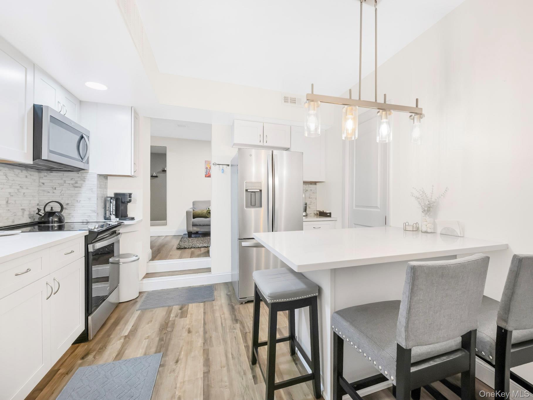 248 Rockne Road Yonkers, NY 10701 - Photo 16 of 40 Kitchen featuring appliances with stainless steel finishes, a breakfast bar, tasteful backsplash, white cabinets, and a peninsula