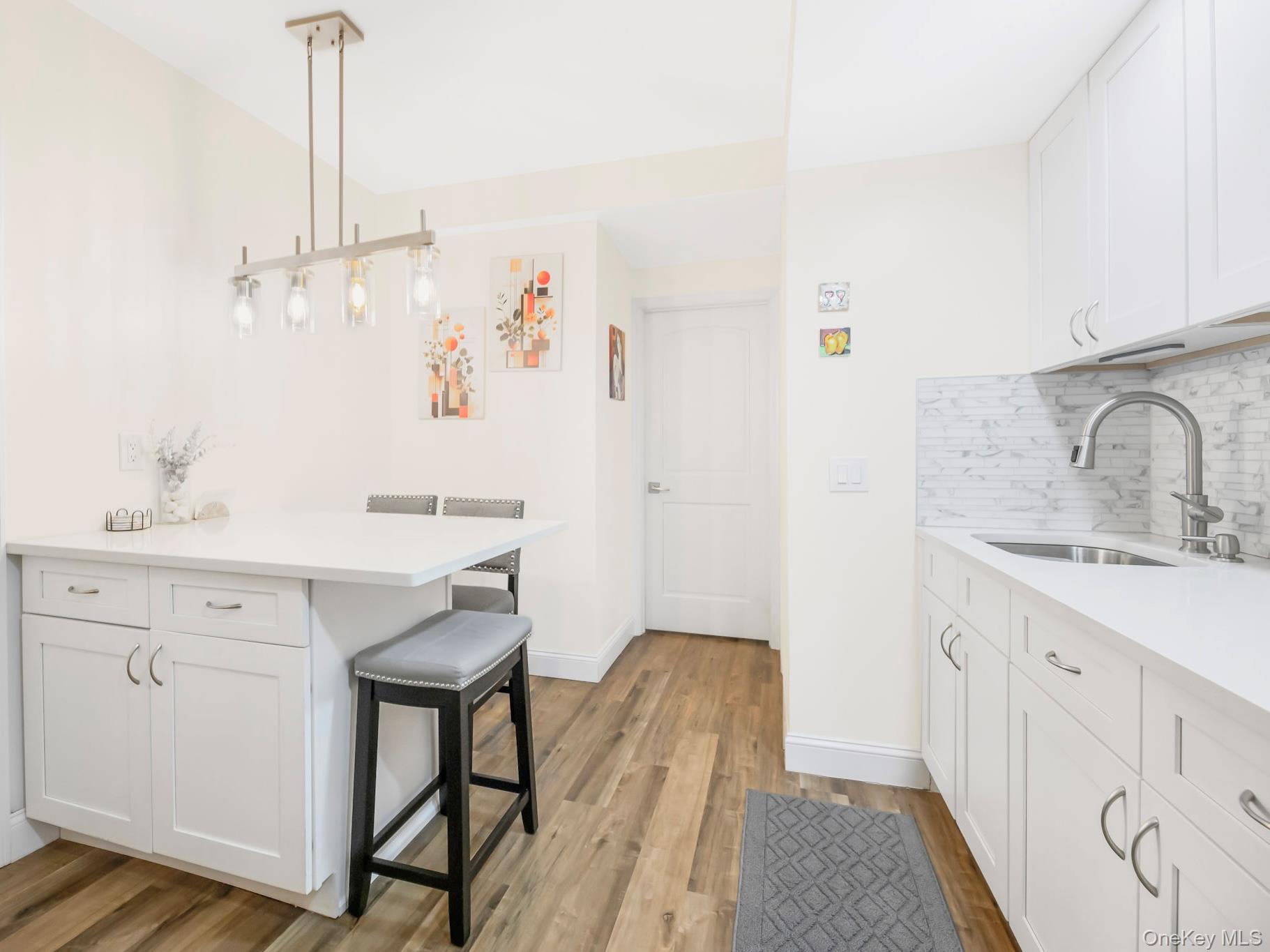 248 Rockne Road Yonkers, NY 10701 - Photo 18 of 40 Kitchen with white cabinets, decorative light fixtures, a breakfast bar area, a peninsula, and tasteful backsplash