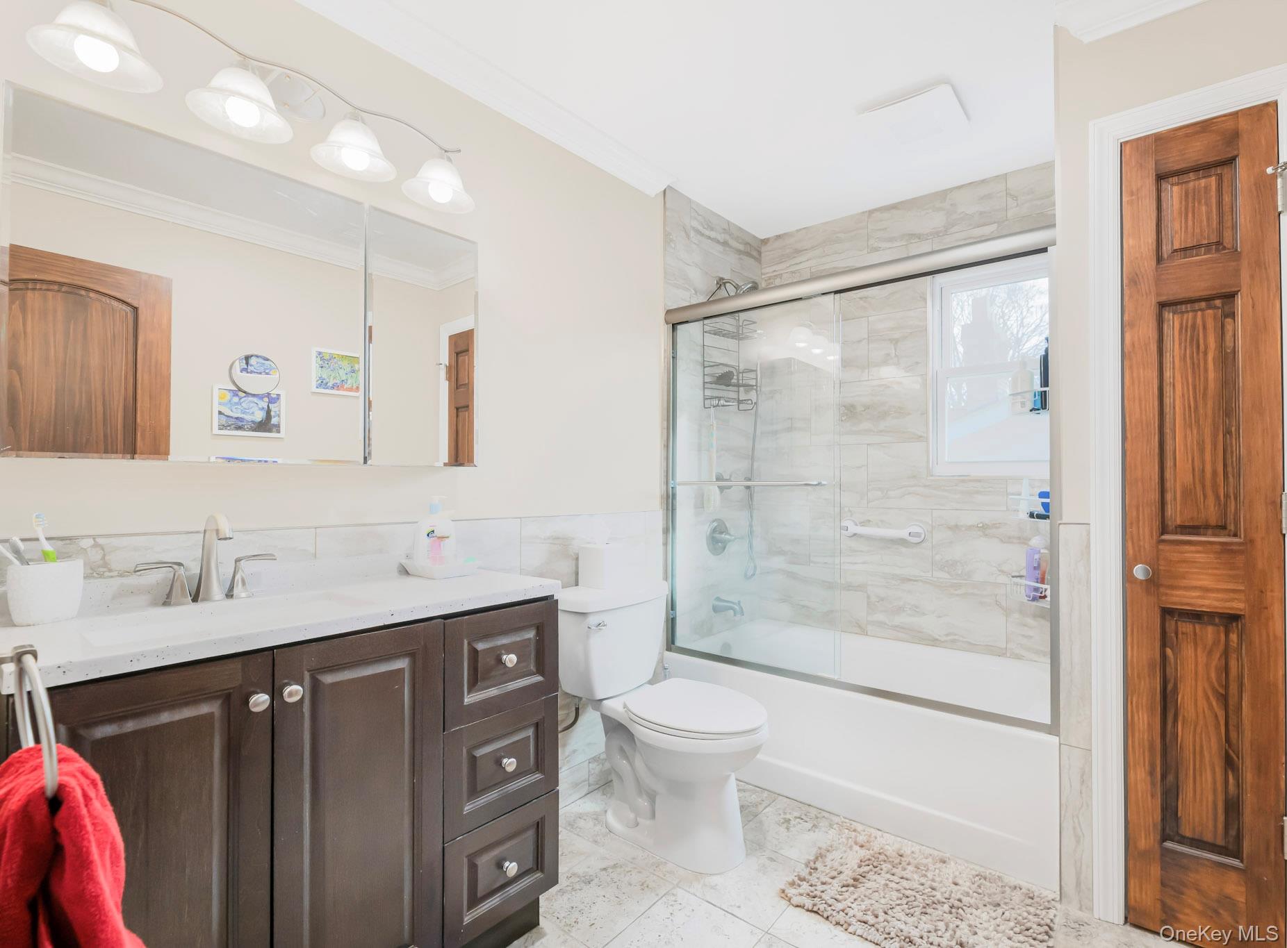 248 Rockne Road Yonkers, NY 10701 - Photo 35 of 40 Full bathroom with vanity, bath / shower combo with glass door, crown molding, tile walls, and wainscoting