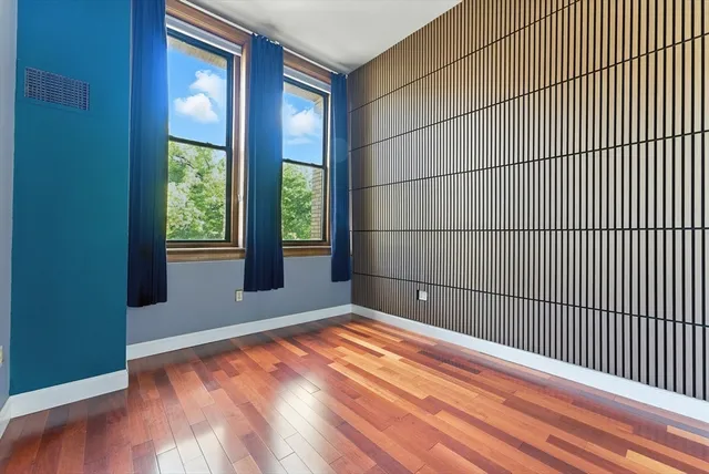 a view of an empty room with wooden floor and a window