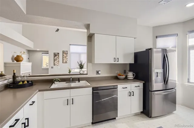 a kitchen with granite countertop a sink a stove a refrigerator and white cabinets