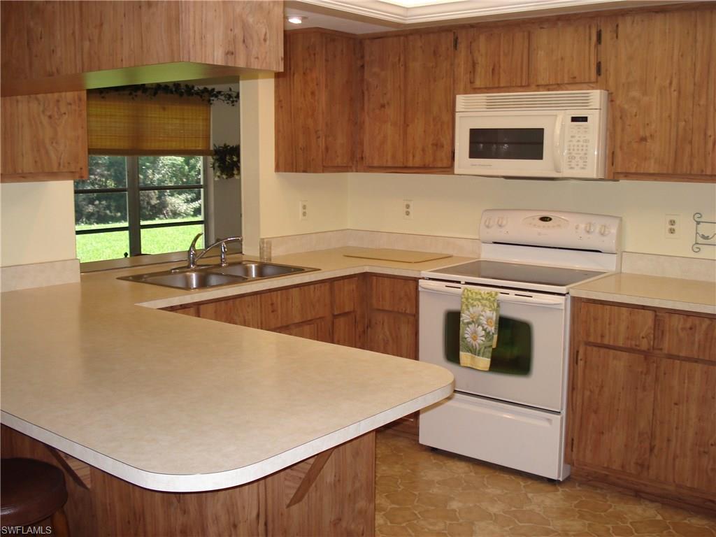 18057 Laurel Valley Road Fort Myers, FL 33967 - Photo 7 of 25 a kitchen with stainless steel appliances a stove a microwave sink and cabinets