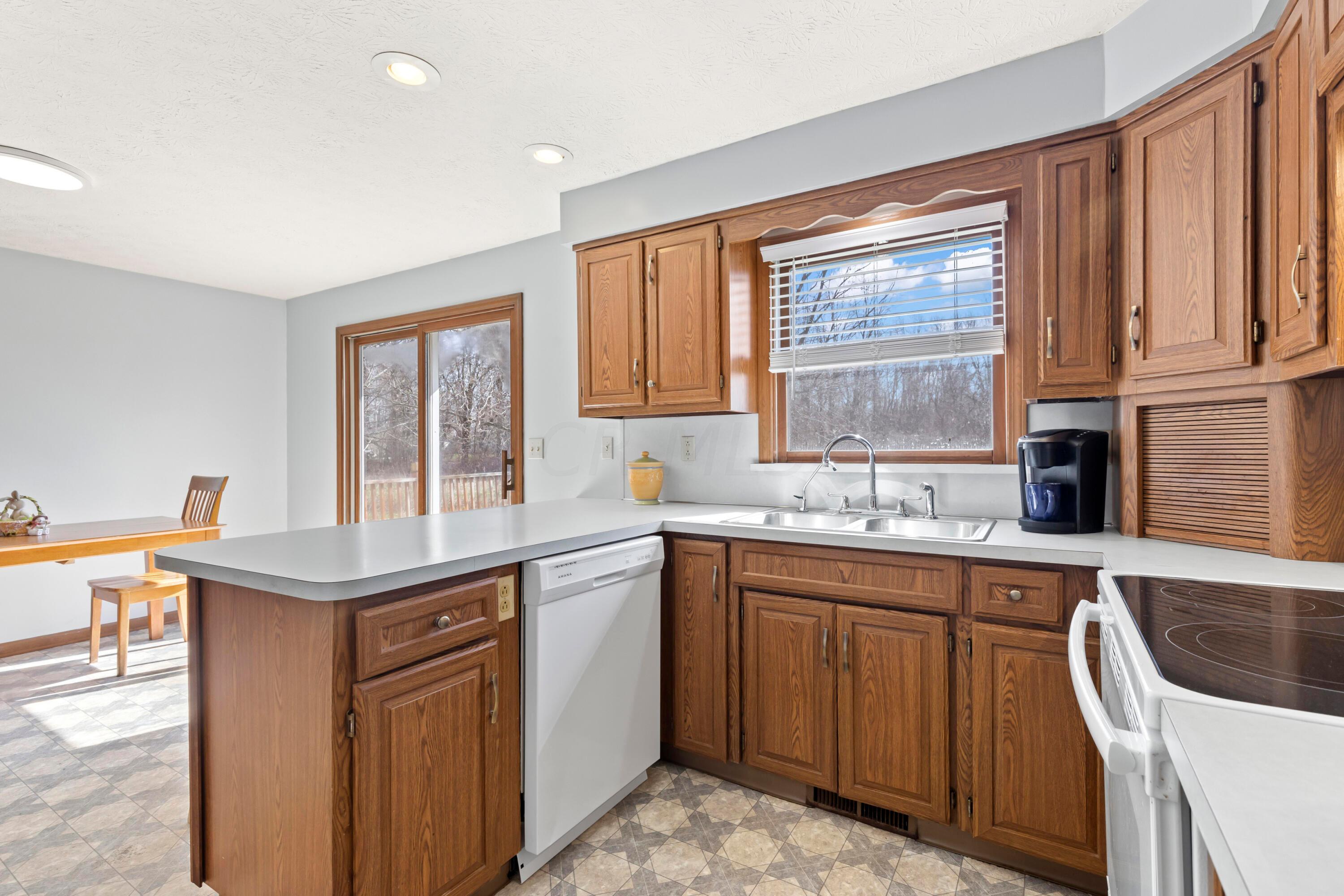 14040 Downing Road Croton, OH 43013 - Photo 23 of 66 • Neutral vinyl flooring
• Light blue painted walls
• Oak cabinets
• Ceiling light
• New General Electric® electric
range ~ 2020
• Kenmore® refrigerator
• New Amana® dishwasher
~ 4/2023
• Double bowl, stainless steel sink
with sprayer & water dispenser
• Disposal
• Pantry closet