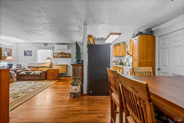 a living room with stainless steel appliances furniture a flat screen tv and a table