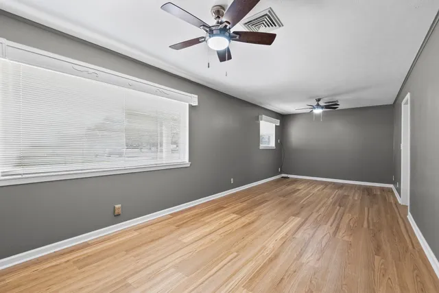 a view of an empty room with a window and wooden floor