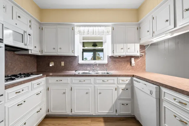 a kitchen with granite countertop white cabinets and white appliances
