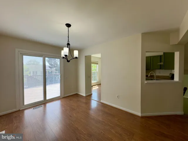a view of a livingroom with wooden floor a ceiling fan and windows