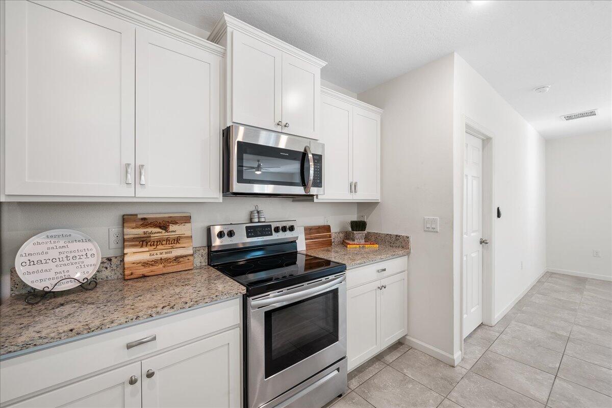 710 Old Country Rd S East Palm Bay, FL 32909 - Photo 4 of 27 a kitchen with granite countertop white cabinets and stainless steel appliances
