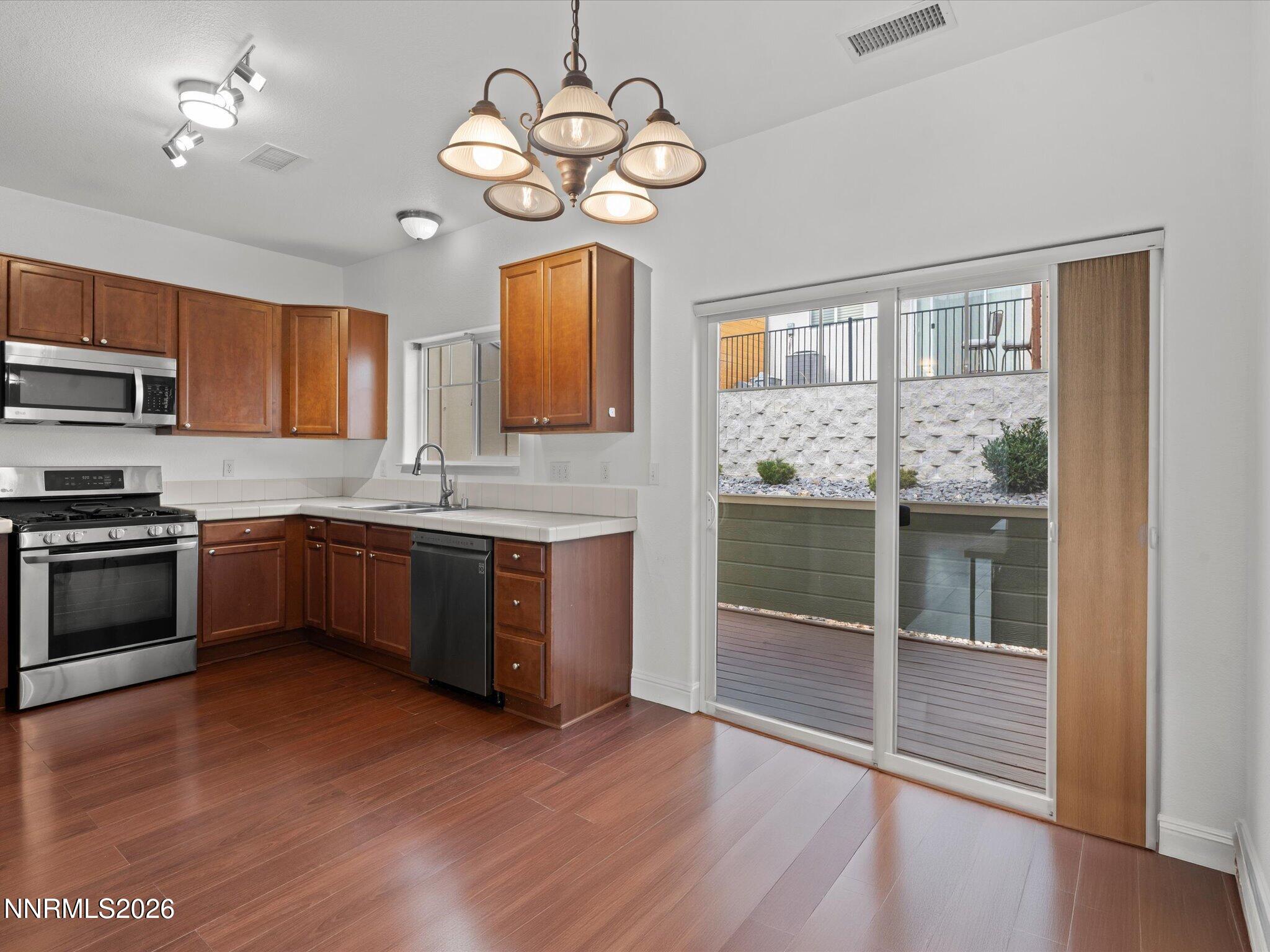 4795 Ciarra Kennedy Lane Reno, NV 89503 - Photo 13 of 37 a kitchen with stainless steel appliances granite countertop wooden floors a stove a sink and dishwasher