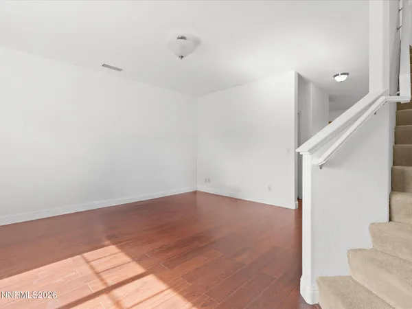 a view of an empty room with wooden floor and windows