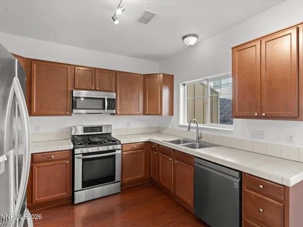 a kitchen with stainless steel appliances a sink cabinets and a window