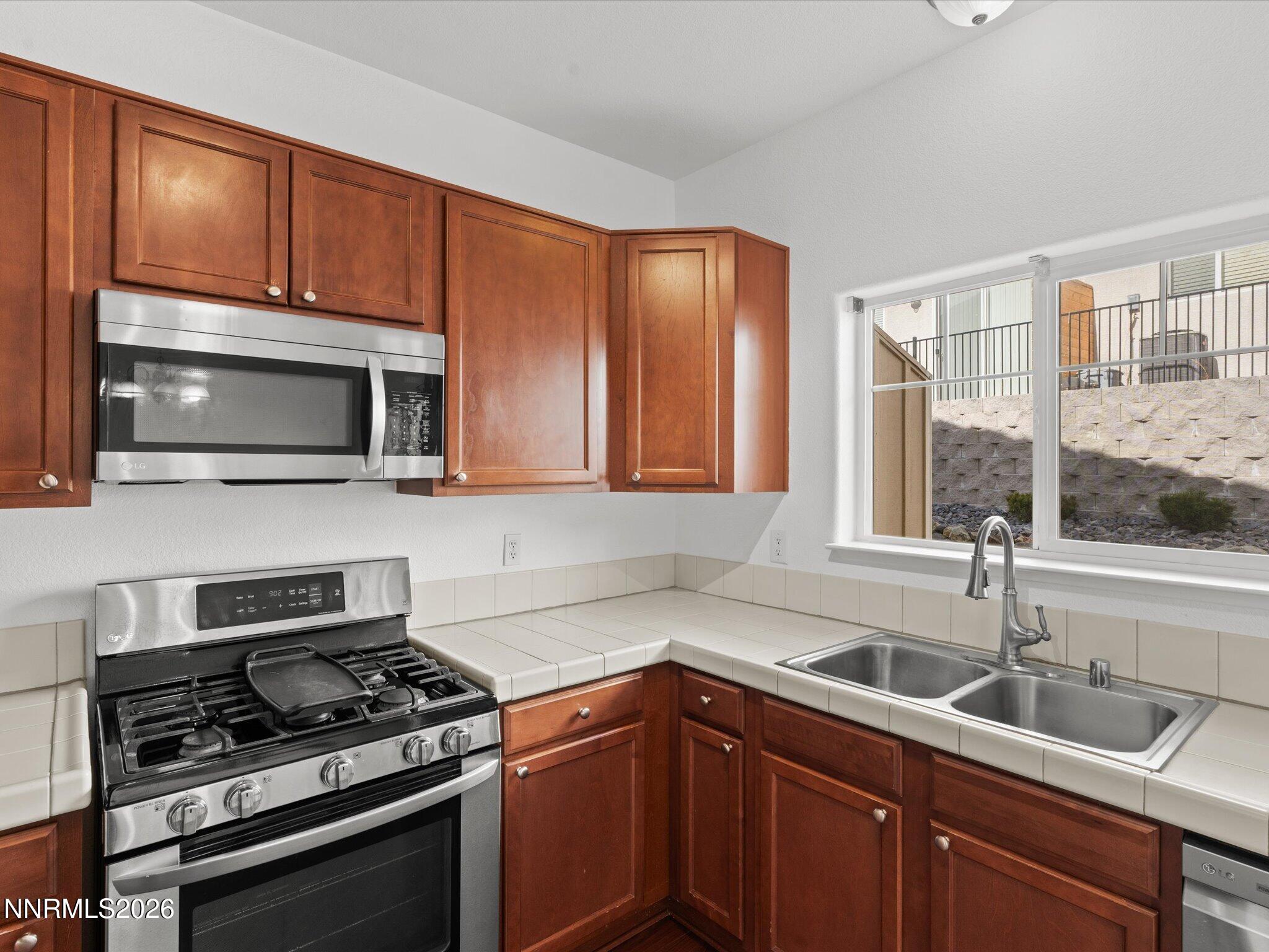 4795 Ciarra Kennedy Lane Reno, NV 89503 - Photo 24 of 37 a kitchen with stainless steel appliances a stove sink microwave and cabinets