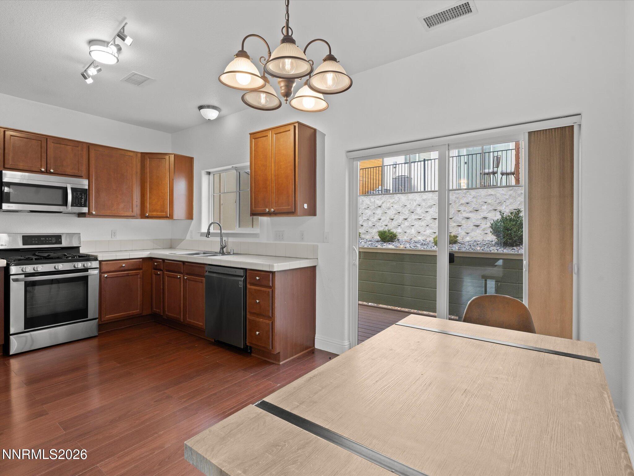 4795 Ciarra Kennedy Lane Reno, NV 89503 - Photo 6 of 37 a kitchen with a stove a sink dishwasher a kitchen island with wooden cabinets and floor
