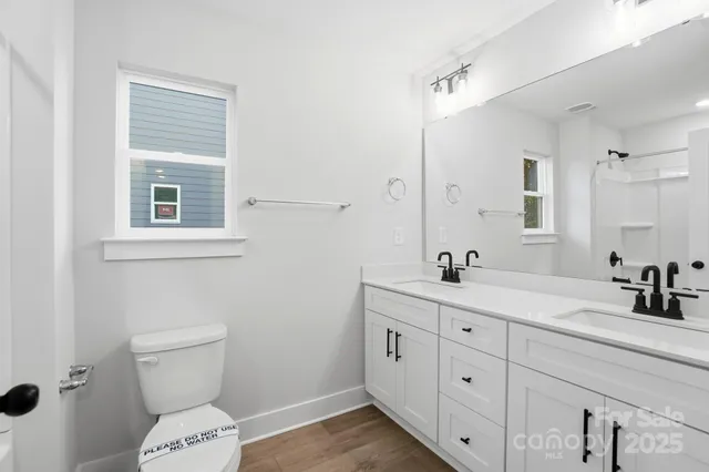 a bathroom with a double vanity sink toilet and a mirror