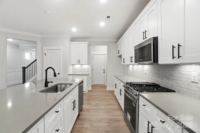 a kitchen with kitchen island stainless steel appliances a sink stove top oven and refrigerator