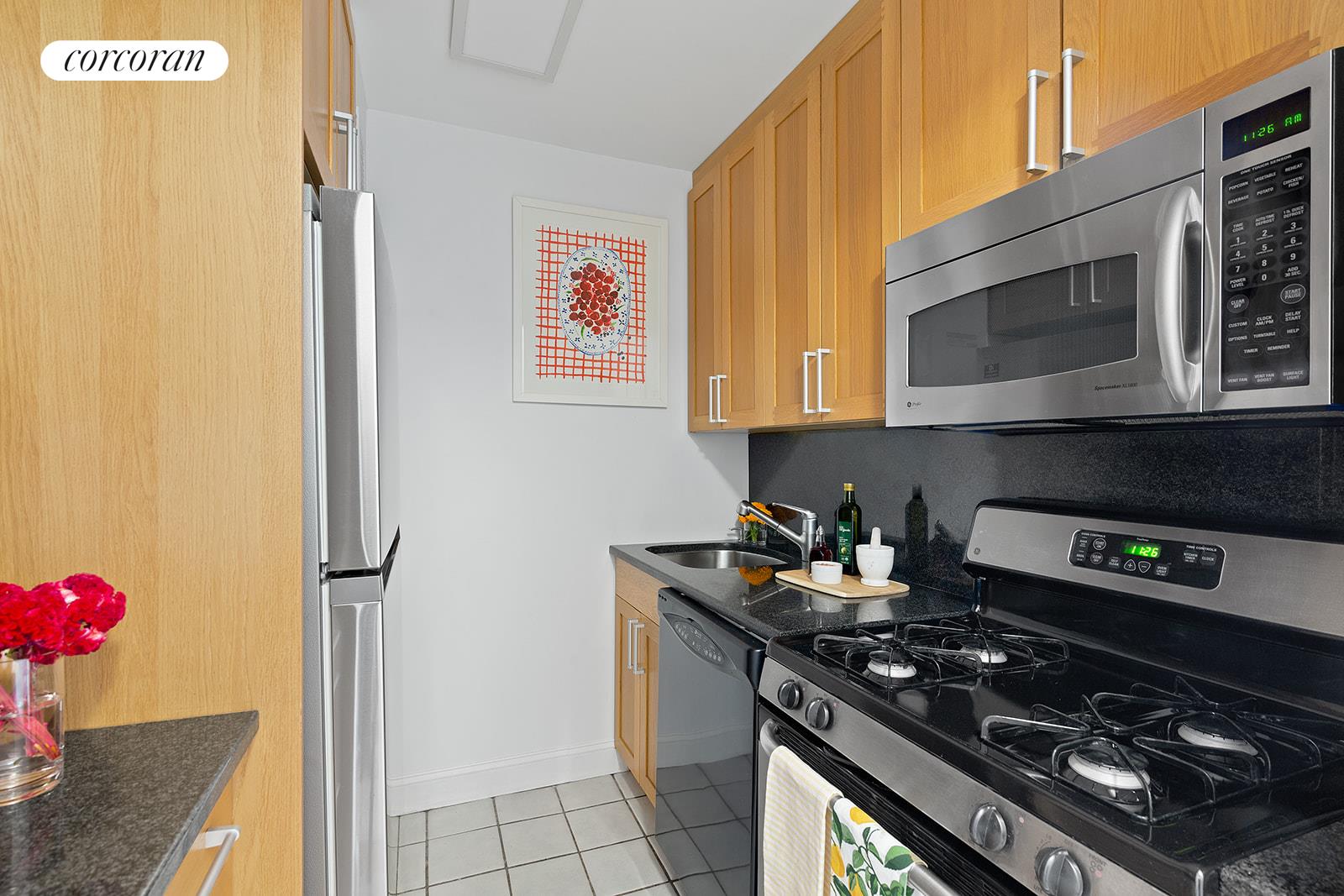 2025 Broadway, Unit 17F Manhattan, NY 10023 - Photo 13 of 15 a kitchen with stainless steel appliances granite countertop a stove a microwave and cabinets