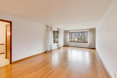 an empty room with wooden floor ceiling fan and windows