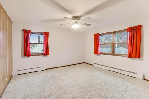 an empty room with windows and fan