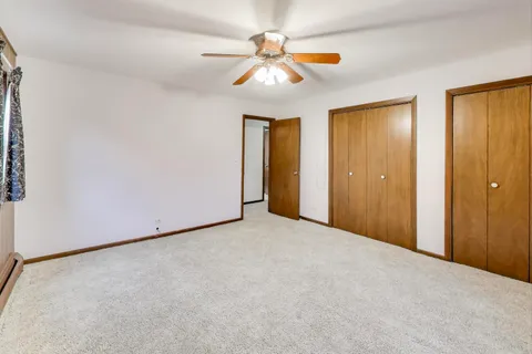 an empty room with closet and a ceiling fan