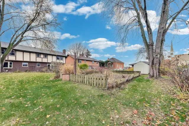 a view of a house with a yard and a large tree