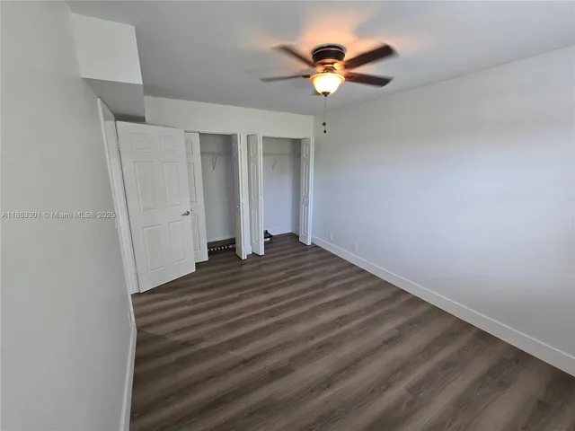 an empty room with wooden floor ceiling fan and window
