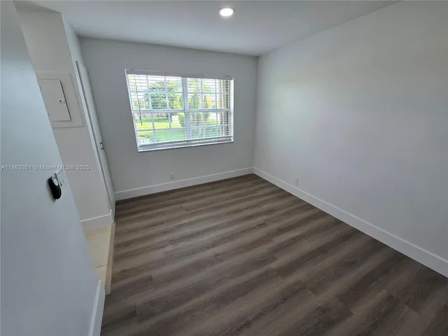 a view of an empty room with wooden floor and window