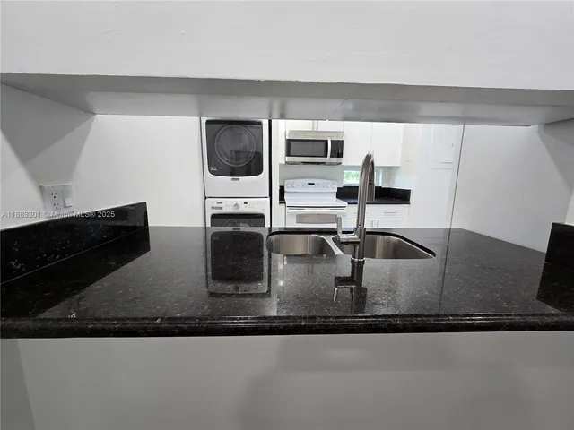 a kitchen with stainless steel appliances granite countertop a sink a microwave a stove and white cabinets