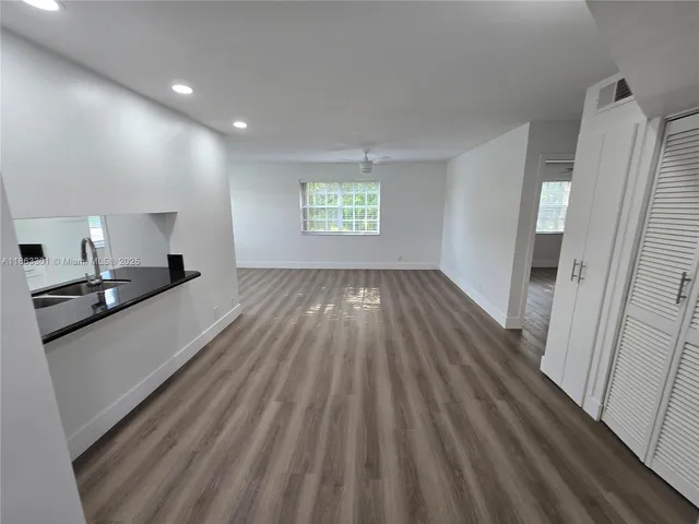 a view of a kitchen with stainless steel appliances wooden floor and a large window