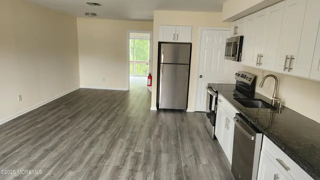 a kitchen with granite countertop wooden floors a sink and a window