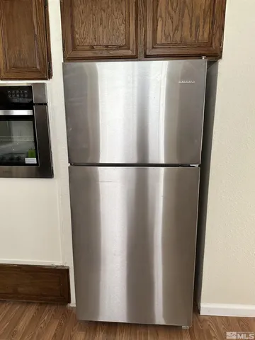 a close view of a refrigerator in kitchen with stainless steel appliances wooden floor
