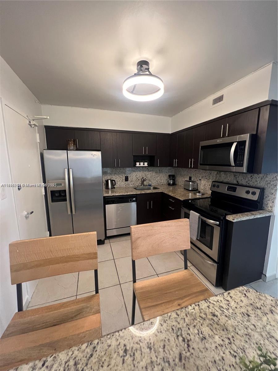 5161 Collins Avenue, Unit 1211 Miami Beach, FL 33140 - Photo 7 of 29 a kitchen with stainless steel appliances kitchen island granite countertop a refrigerator and a stove top oven