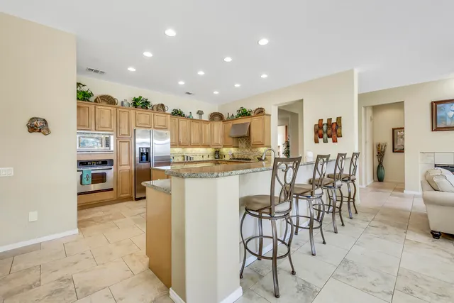 a kitchen with stainless steel appliances kitchen island granite countertop a refrigerator and cabinets