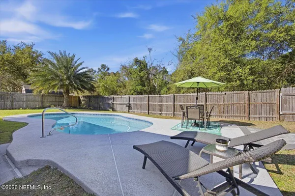a view of a backyard with swimming pool and sitting area