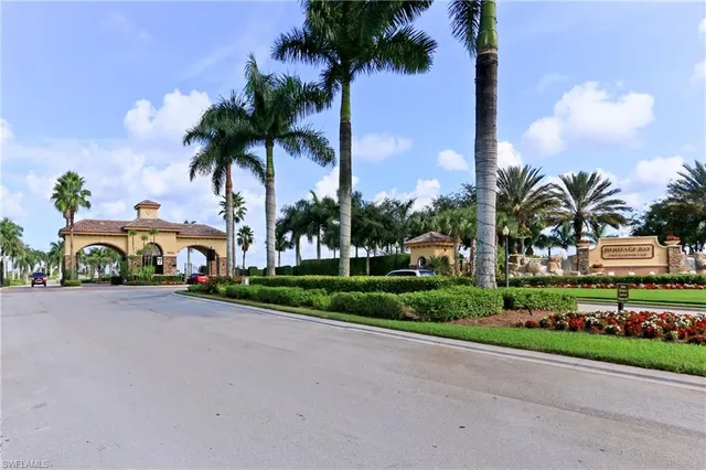 a front view of yellow house with a yard and palm trees