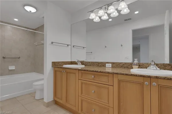 a bathroom with a granite countertop sink a toilet and bathtub