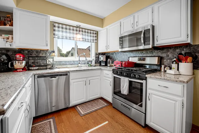 a kitchen with stainless steel appliances granite countertop a stove a sink and a microwave