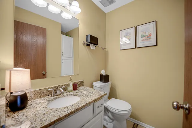 a bathroom with a granite countertop toilet a sink and a mirror