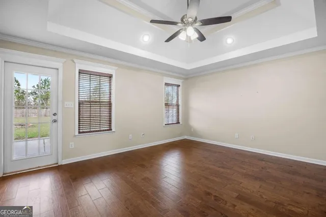 a view of an empty room with wooden floor and windows