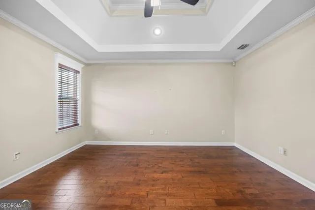 a view of an empty room with window and wooden floor