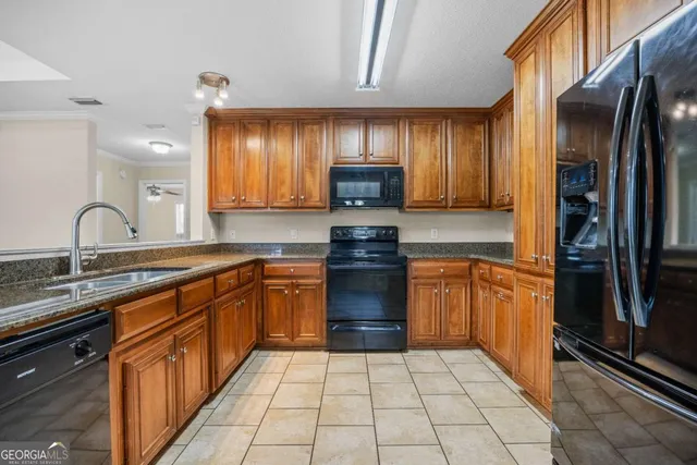 a kitchen with granite countertop a refrigerator and a stove top oven
