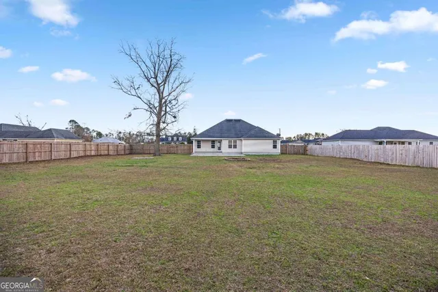 a view of a yard in front of a house with a large tree
