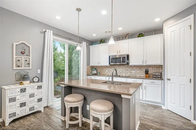 a kitchen with stainless steel appliances granite countertop a stove a sink refrigerator and white cabinets with wooden floor