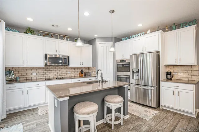 a kitchen with a refrigerator a sink and chairs