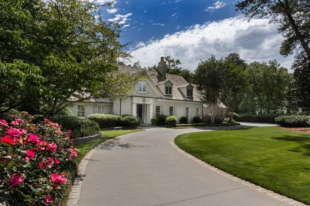 a front view of a house with a garden and trees