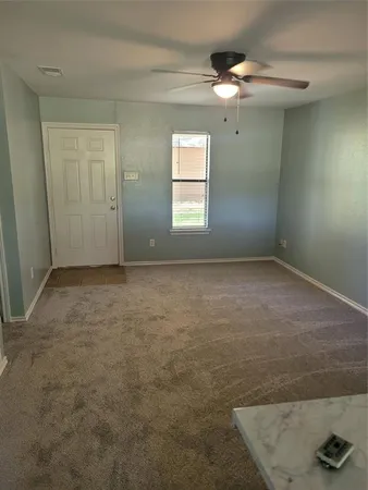 an empty room with windows and fan