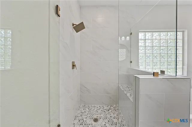 a bathroom with a bathtub a shower and a window